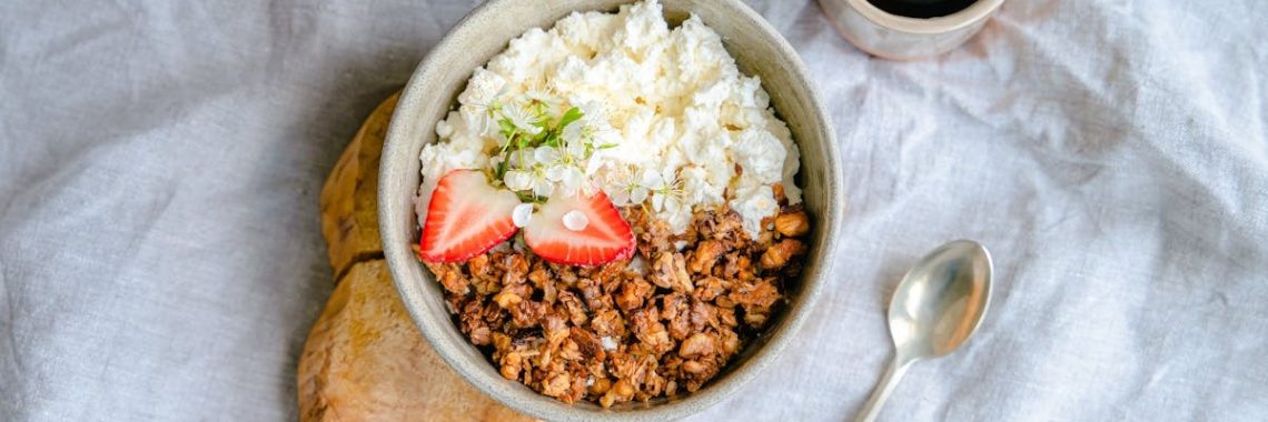 A delicious breakfast bowl with cottage cheese, granola, and strawberries served with black coffee.